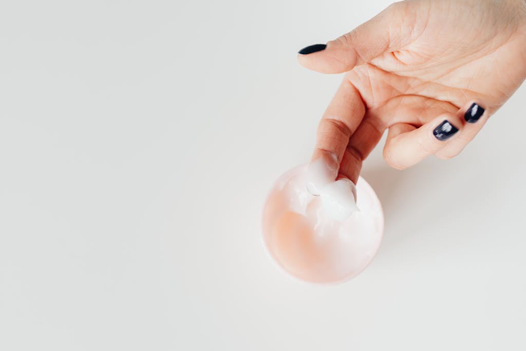 A close-up view of a hand applying cream with neatly manicured nails, perfect for skincare concepts.