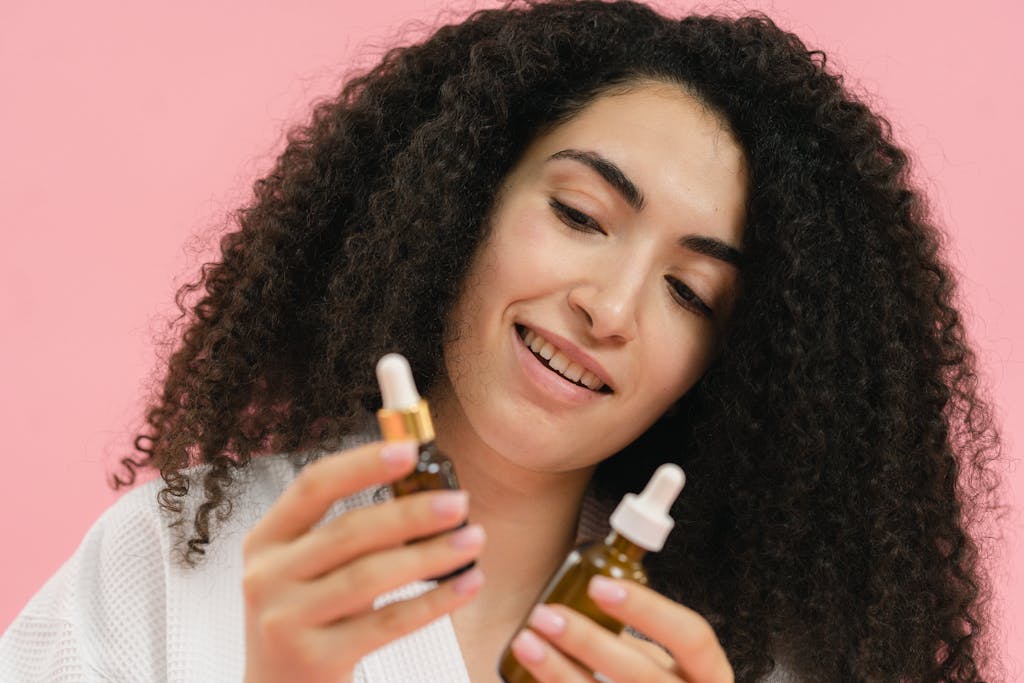 A young woman analyzes skincare bottles, set against a pink backdrop.