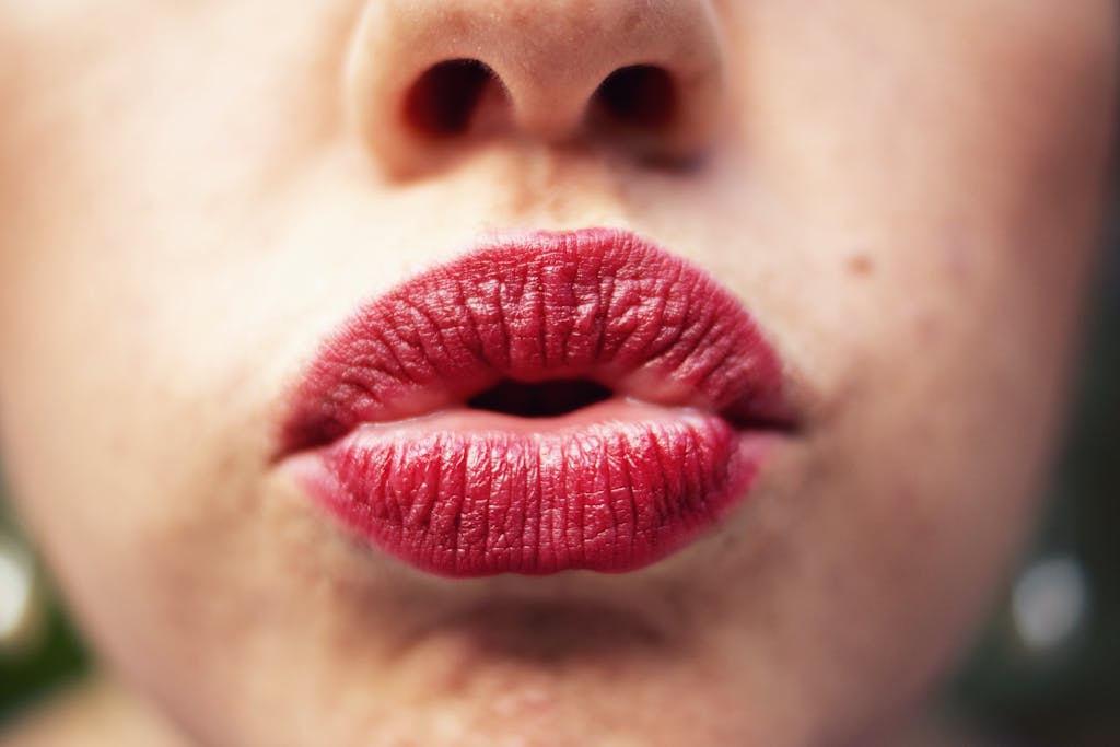 An artistic close-up of red lips in a pout, highlighting makeup and texture.
