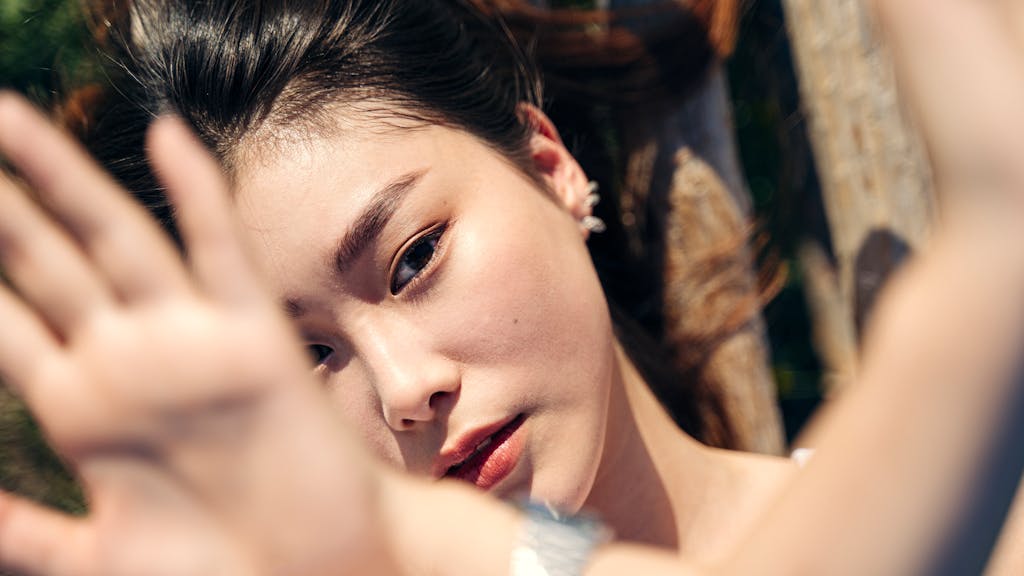 Artistic close-up of a woman's face with sunlight and hand shading.