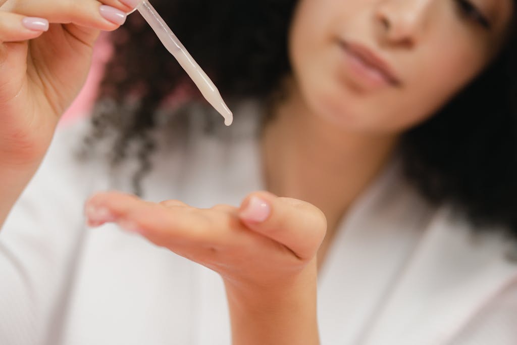 Close-up of a woman applying skincare serum with a pipette, focusing on body care and cosmetic application.