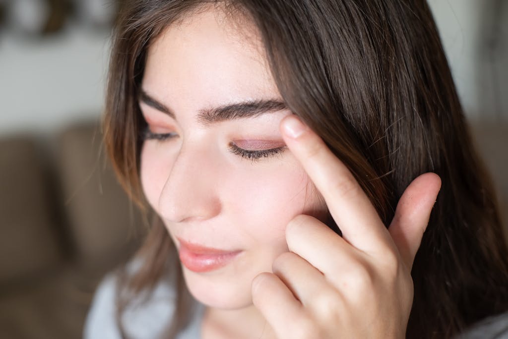 Close-up portrait of a woman touching her eyelid showcasing natural eye makeup.