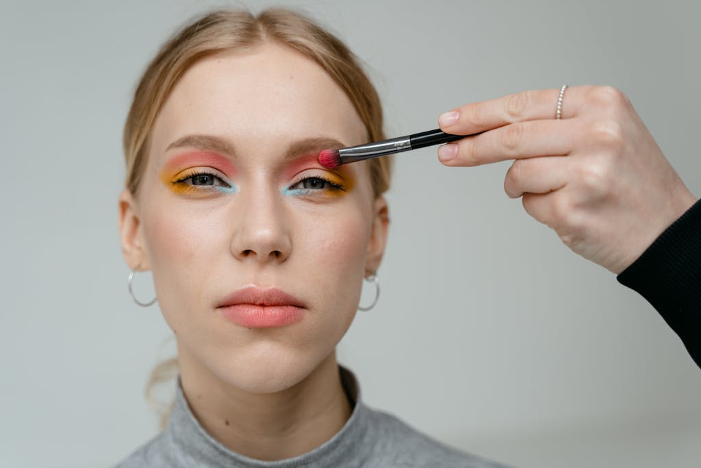 Close-up portrait of a woman with vibrant eyeshadow applied with a brush.