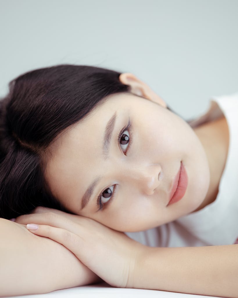 Close-up portrait of a young Asian woman lying down, exuding calmness and delicacy.
