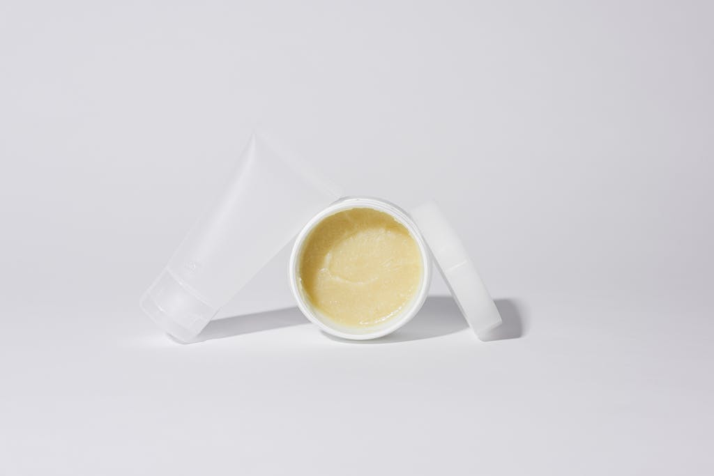 Studio shot of white plastic containers with yellow cream product on a white background.