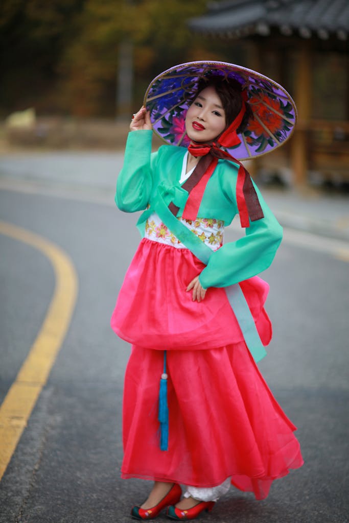 Woman in vibrant Korean hanbok posing on a country road, showcasing cultural dress.