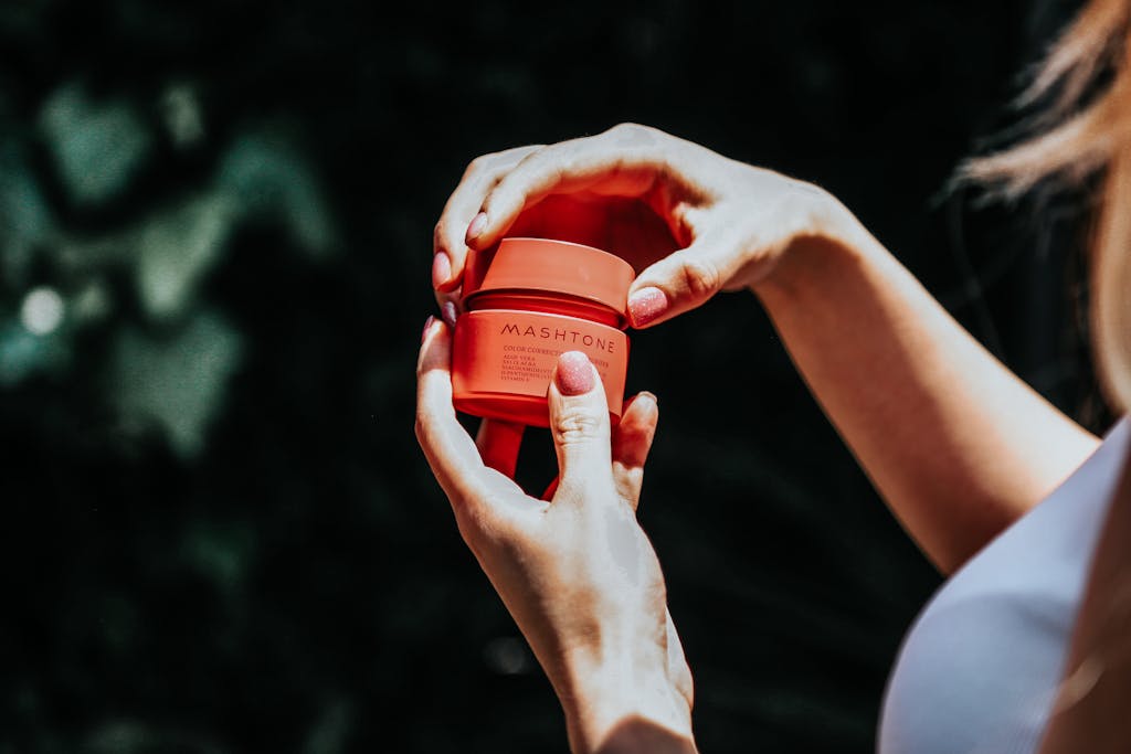 A close-up of female hands holding a skincare jar outdoors, highlighting beauty and skincare concepts.