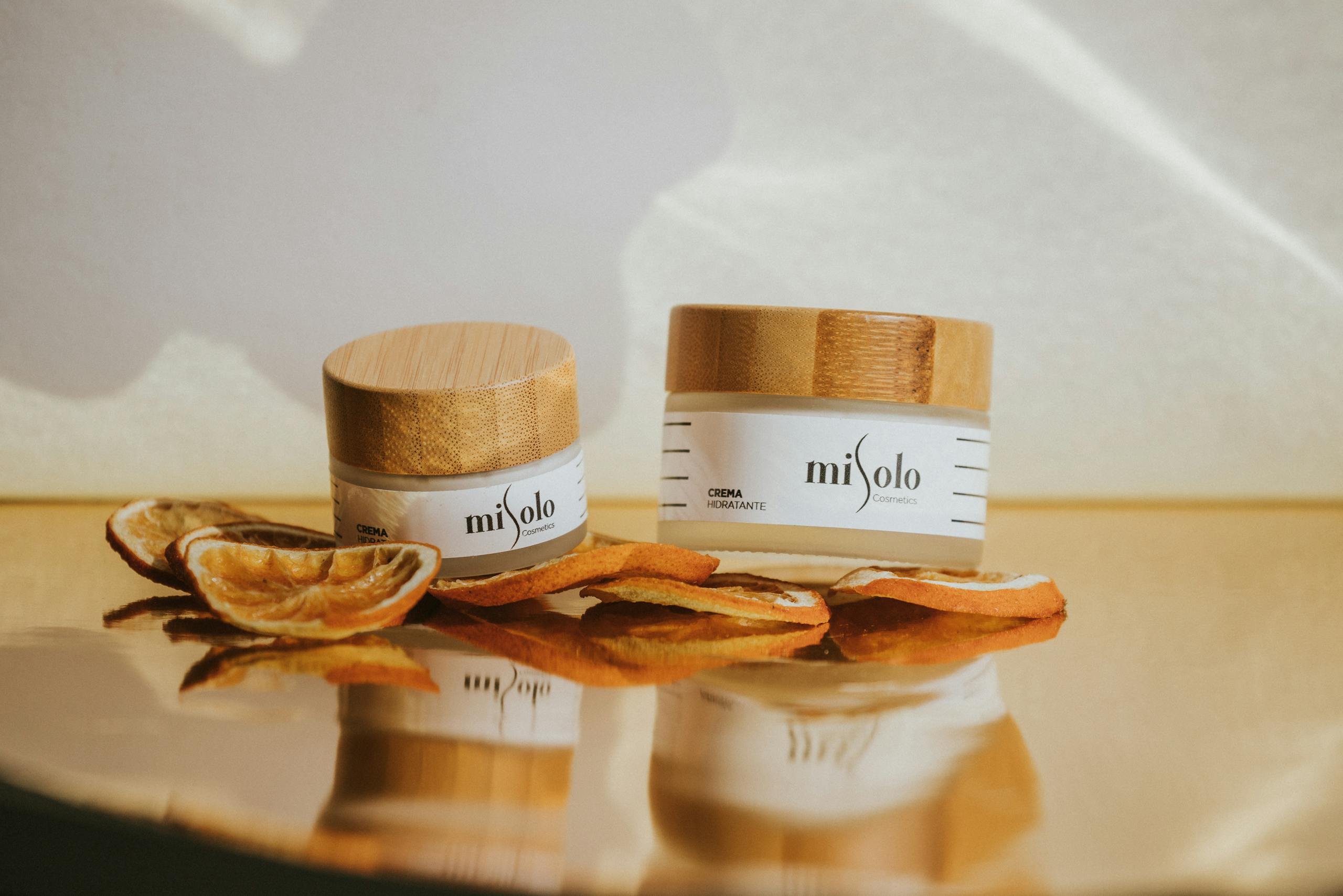 Moisturizing cream jars with natural bamboo lids, accented by dried orange slices.