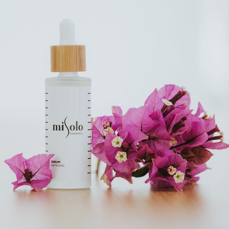 Sophisticated cosmetic serum bottle beside vibrant bougainvillea flowers, perfect for beauty themes.