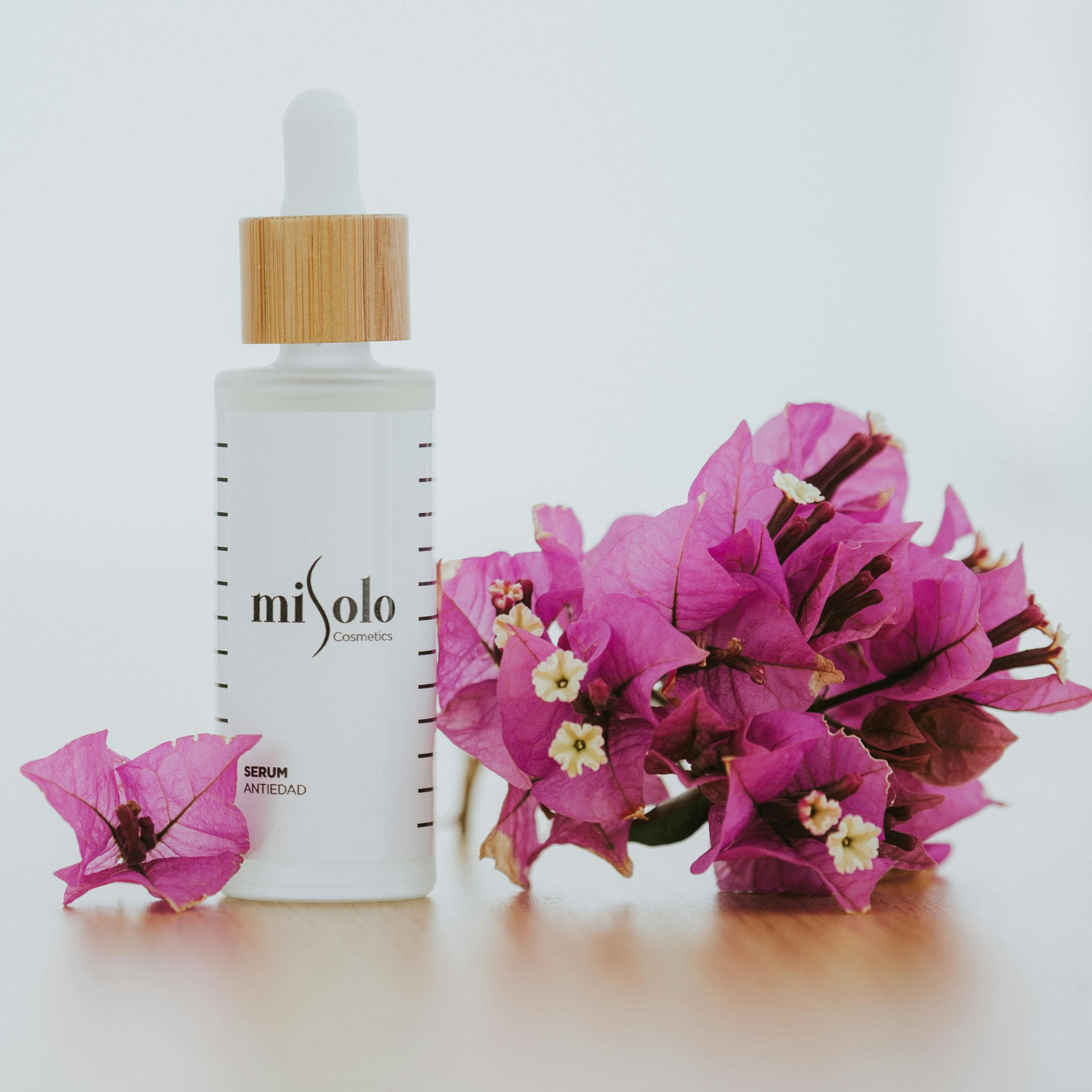 Sophisticated cosmetic serum bottle beside vibrant bougainvillea flowers, perfect for beauty themes.