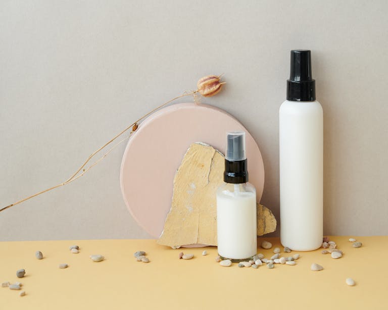 Stylish skincare product showcase with spray bottles and pebbles.