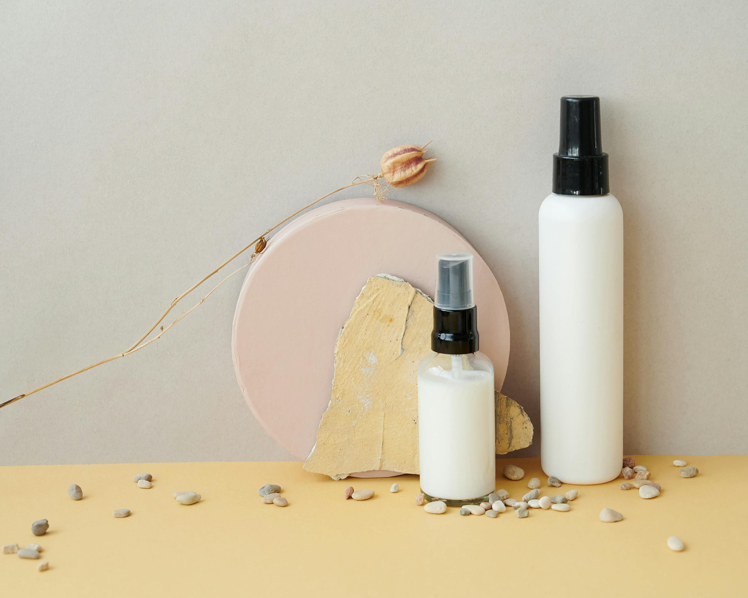 Stylish skincare product showcase with spray bottles and pebbles.