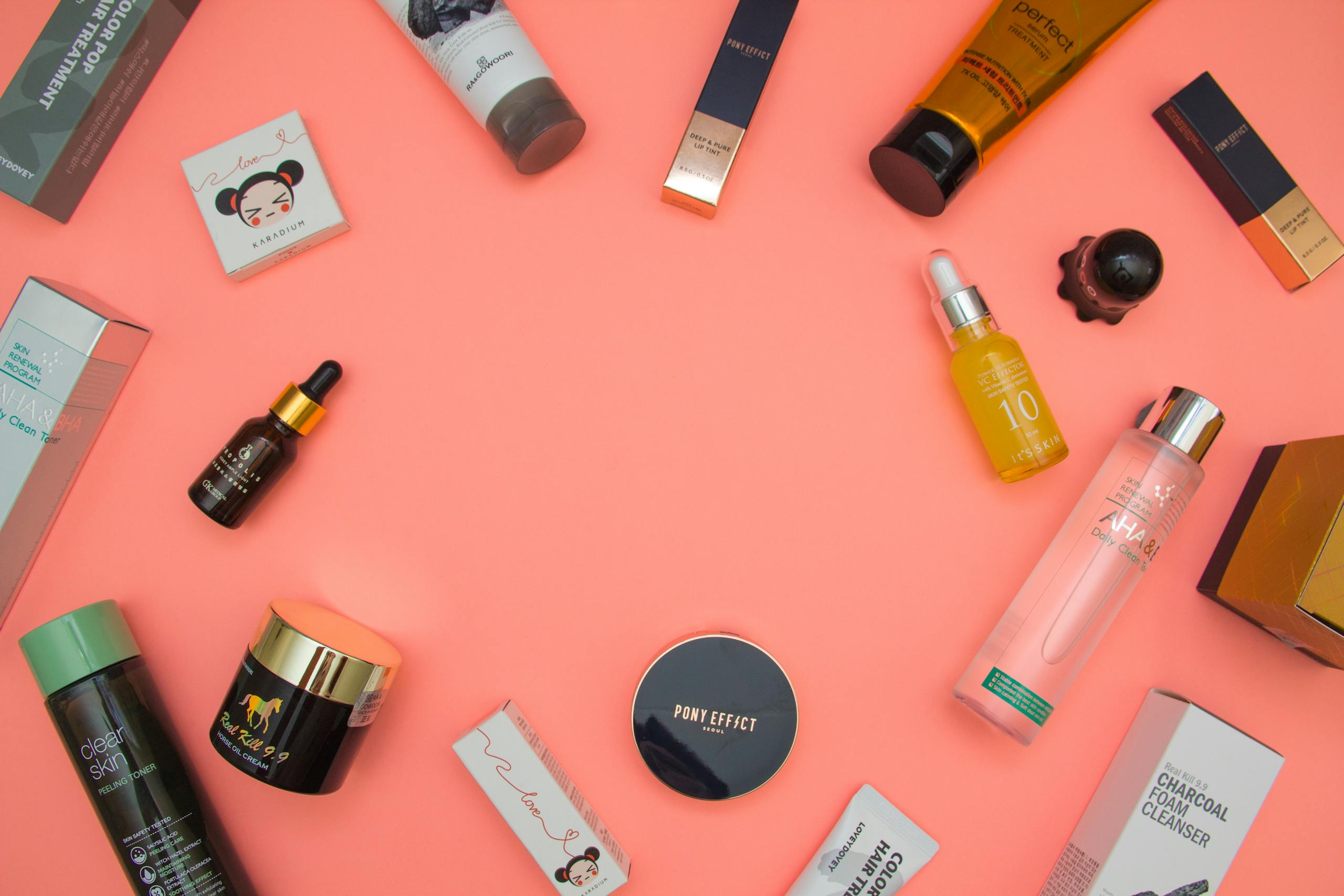 Top view of various cosmetic products for skincare and beauty in different bottles placed on pink surface