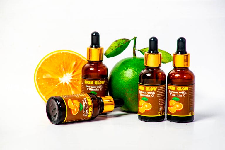 Vitamin C serum bottles with fresh citrus fruits for skincare and health promotion.
