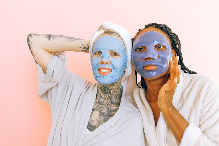 Women enjoying skincare routine with colorful face masks and robes.